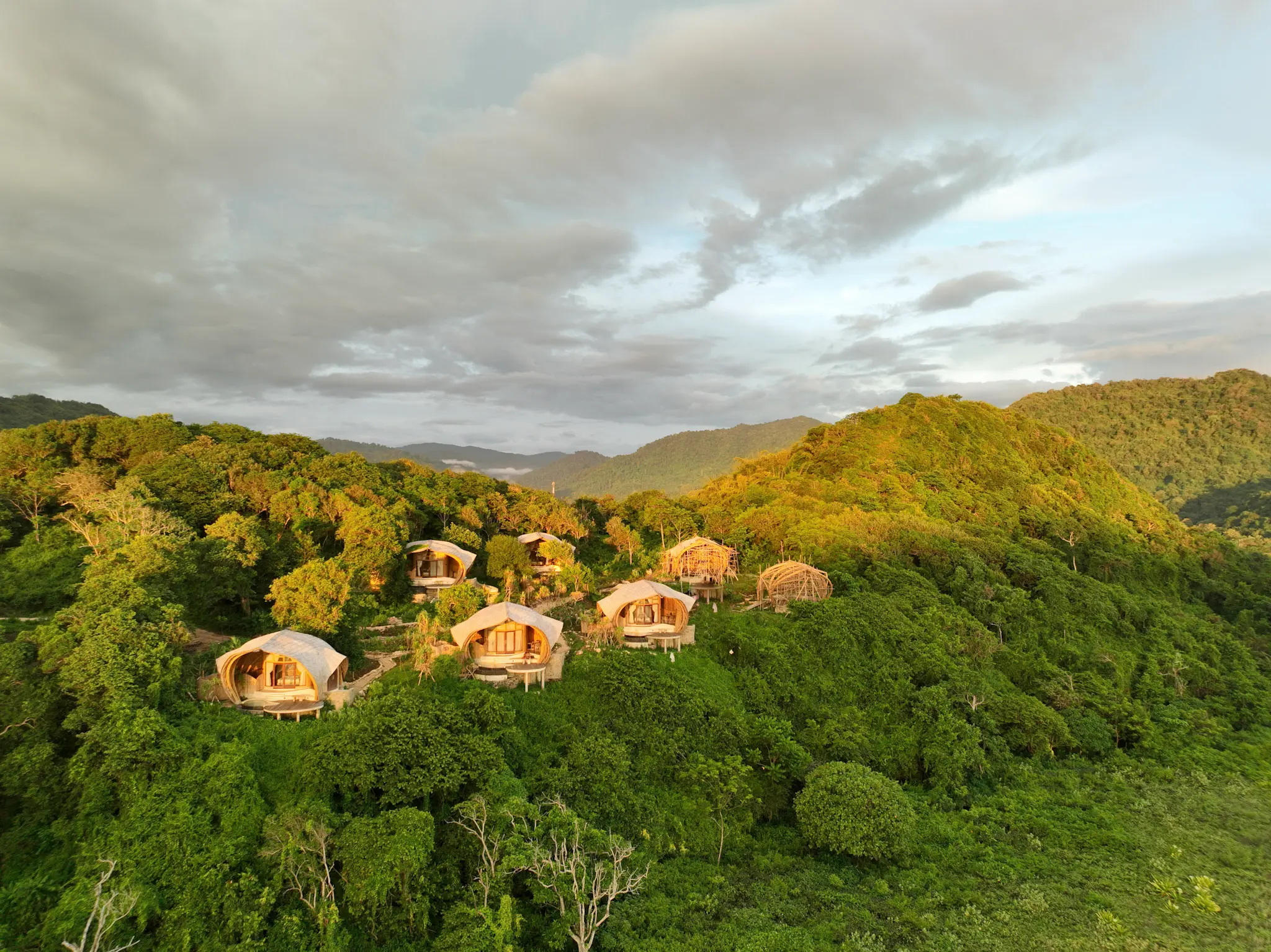Aerial overview of Eco Bamboo Beach Front lodges at Kini Resort surrounded by jungle above the Indian Ocean, West Sumbawa Indonesia