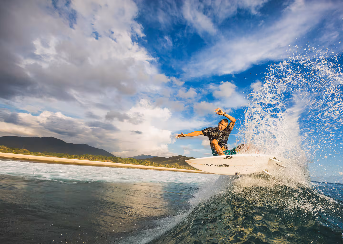 Surfer riding a wave at Yoyo's surf break in front of Kini Resort Sumbawa — uncrowded beachfront surf with jungle backdrop